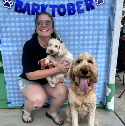 Dr. Heather Yardley smiling at a Barktober event holding two dogs
