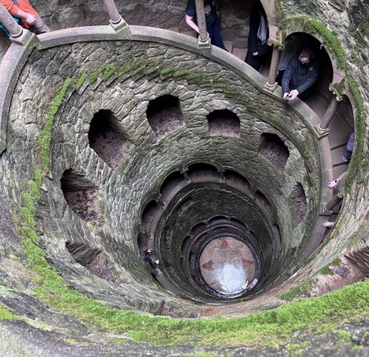 Aerial view of a spiral stone staircase tower with moss-covered walls